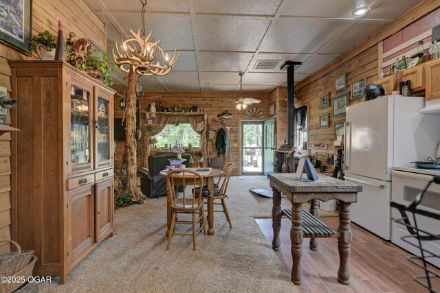 9404 County Lane 121, Carthage, MO 64836 - dining area with wooden walls, a chandelier, a wood stove, and light carpet