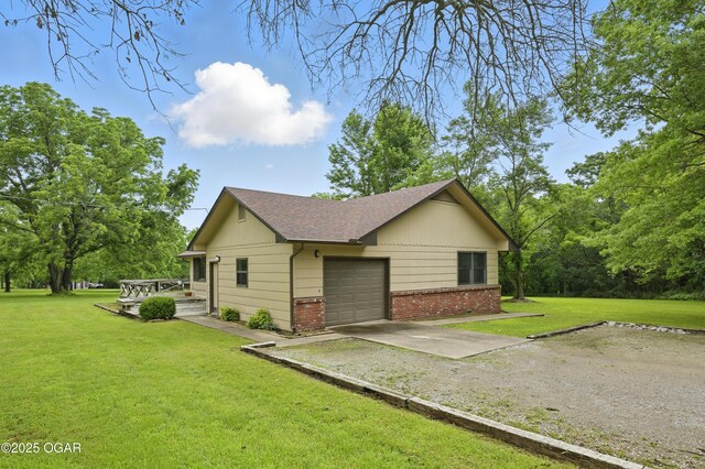 5694 Spurgeon Rd, Joplin, MO 64804 - view of property exterior featuring driveway, a garage, brick siding, a yard, and a shingled roof