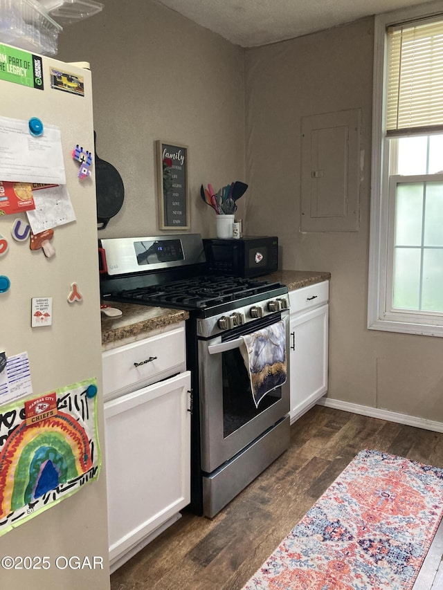 524 W 2nd St, Webb City, MO 64870 - kitchen featuring gas range, freestanding refrigerator, electric panel, black microwave, and white cabinetry