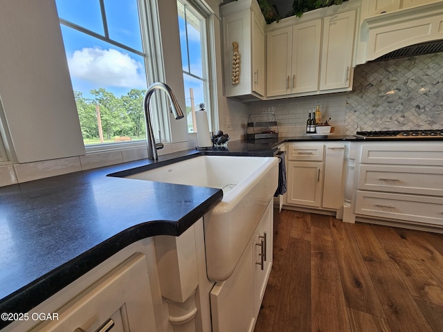 12673 Ibex Rd, Neosho, MO 64850 - kitchen with premium range hood, white cabinetry, decorative backsplash, stainless steel gas stovetop, and dark countertops