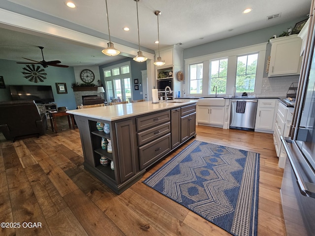 12673 Ibex Rd, Neosho, MO 64850 - kitchen featuring stainless steel dishwasher, a large fireplace, healthy amount of natural light, white cabinetry, and recessed lighting