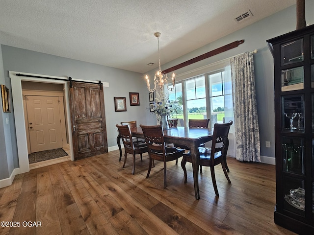 12673 Ibex Rd, Neosho, MO 64850 - dining room featuring a barn door, hardwood / wood-style flooring, a chandelier, and a textured ceiling