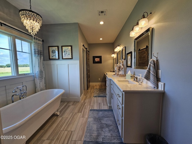 12673 Ibex Rd, Neosho, MO 64850 - bathroom featuring double vanity, a soaking tub, a chandelier, recessed lighting, and a wainscoted wall