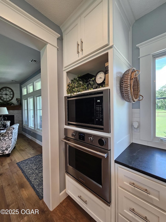 12673 Ibex Rd, Neosho, MO 64850 - kitchen featuring oven, dark wood-style floors, and white cabinetry