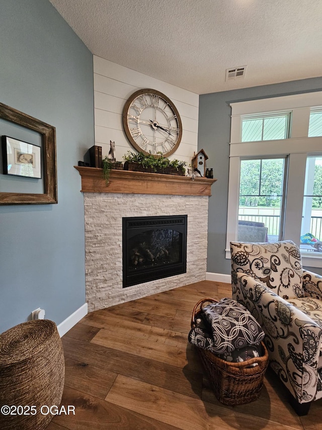12673 Ibex Rd, Neosho, MO 64850 - living room featuring a stone fireplace, wood finished floors, and a textured ceiling