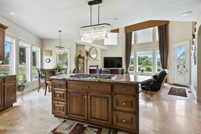 1641 Alexandra Dr, Carthage, MO 64836 - kitchen featuring stainless steel gas stovetop, a chandelier, light tile patterned flooring, light stone counters, and decorative light fixtures