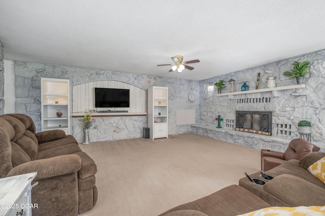 214 S Ozark Trl, Goodman, MO 64843 - living area with a stone fireplace, carpet flooring, ceiling fan, and a textured ceiling