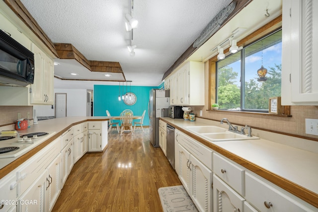 214 S Ozark Trl, Goodman, MO 64843 - kitchen with appliances with stainless steel finishes, white cabinetry, light countertops, wood finished floors, and a textured ceiling