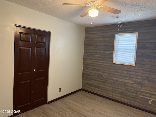 1310 Regan Ave, Carthage, MO 64836 - spare room with wood walls, a textured ceiling, wood finished floors, and a ceiling fan