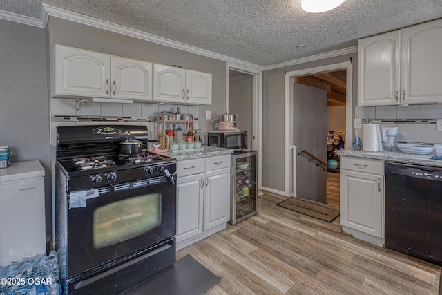 602 N Grand St, Pittsburg, KS 66762 - kitchen featuring black appliances, wine cooler, a textured ceiling, white cabinets, and light wood-style flooring