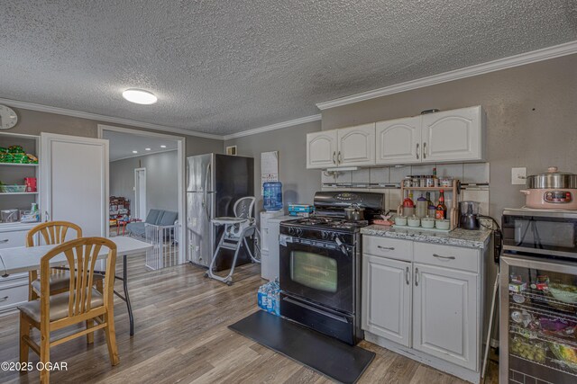 602 N Grand St, Pittsburg, KS 66762 - kitchen featuring stainless steel appliances, white cabinetry, light wood-type flooring, light countertops, and a textured ceiling