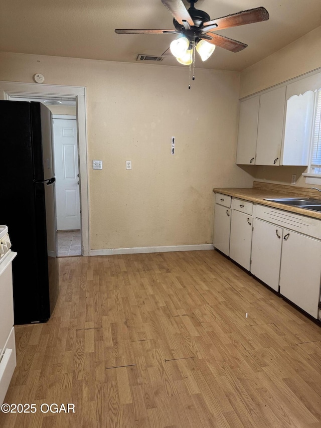 206 N Picher, Joplin, MO 64801 - kitchen featuring freestanding refrigerator, a ceiling fan, white cabinets, and light wood-style flooring
