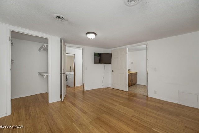 645 Worth St, Granby, MO 64844 - unfurnished bedroom with light wood finished floors, washer / clothes dryer, ensuite bathroom, a walk in closet, and a closet