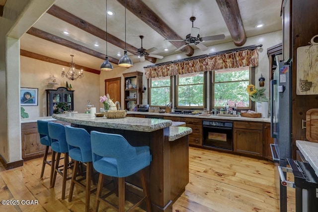 10640 Durango Ln, Carthage, MO 64836 - kitchen featuring oven, beam ceiling, light wood-style flooring, a kitchen island, and a breakfast bar