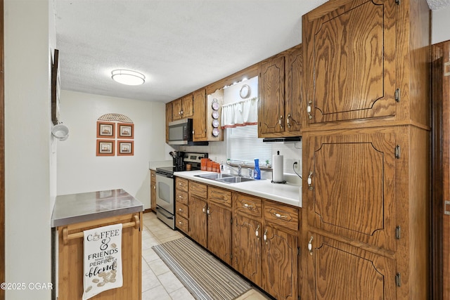 2015 W Zora St, Joplin, MO 64801 - kitchen featuring stainless steel appliances, light tile patterned floors, brown cabinetry, a textured ceiling, and light countertops