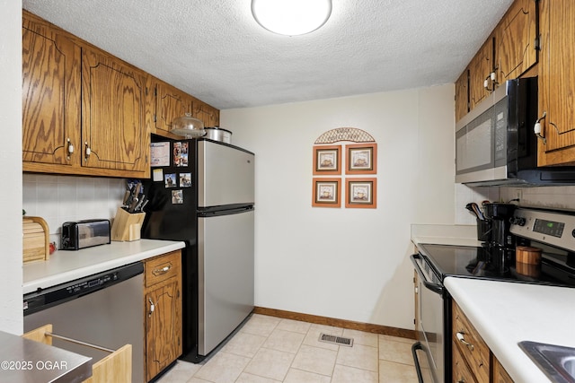 2015 W Zora St, Joplin, MO 64801 - kitchen featuring appliances with stainless steel finishes, brown cabinets, a textured ceiling, light countertops, and light tile patterned floors