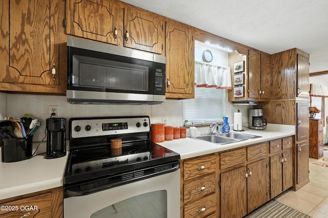 2015 W Zora St, Joplin, MO 64801 - kitchen featuring appliances with stainless steel finishes, brown cabinets, decorative backsplash, light countertops, and a textured ceiling