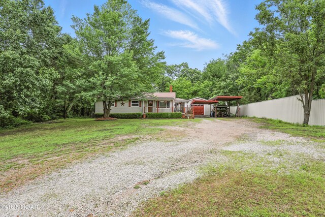 2015 W Zora St, Joplin, MO 64801 - view of front of house featuring gravel driveway, a chimney, a porch, and a detached carport