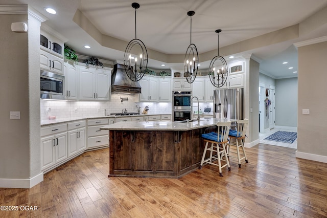 6133 Ridgeview Ct, Joplin, MO 64804 - kitchen with a chandelier, premium range hood, stainless steel appliances, tasteful backsplash, and white cabinets