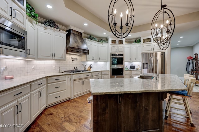 6133 Ridgeview Ct, Joplin, MO 64804 - kitchen featuring appliances with stainless steel finishes, custom exhaust hood, a chandelier, light wood finished floors, and white cabinets