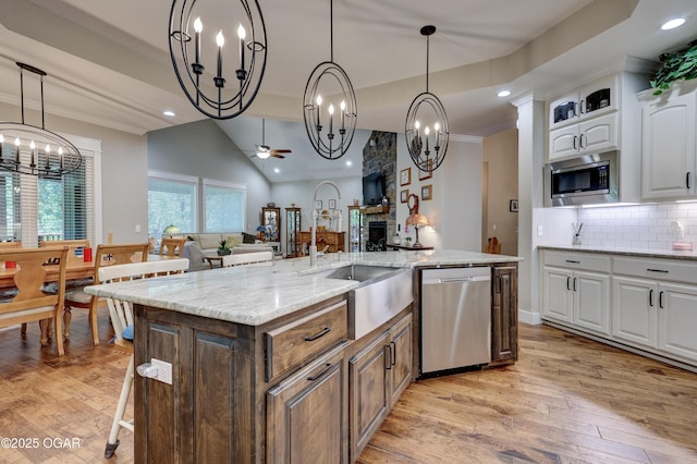 6133 Ridgeview Ct, Joplin, MO 64804 - kitchen featuring stainless steel appliances, a chandelier, white cabinetry, light wood-style floors, and a center island with sink