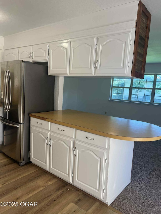 1617 Massachusetts Ave, Joplin, MO 64804 - kitchen with freestanding refrigerator, white cabinets, wood finished floors, and a peninsula