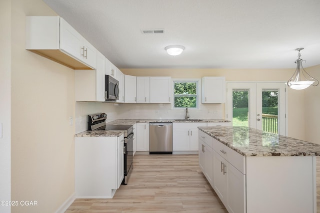 303 Water St, Exeter, MO 65647 - kitchen with appliances with stainless steel finishes, light wood-style flooring, white cabinets, a kitchen island, and light stone counters