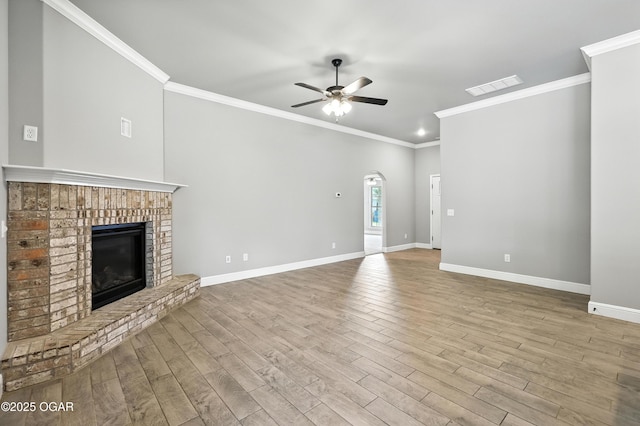2102 S Greystone Sq, Oronogo, MO 64855 - unfurnished living room with a ceiling fan, a brick fireplace, wood finished floors, crown molding, and arched walkways