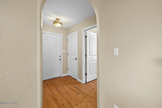 2329 S Willard Ave, Joplin, MO 64804 - hallway featuring arched walkways, a textured wall, and light wood-style floors
