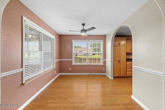 2329 S Willard Ave, Joplin, MO 64804 - unfurnished room featuring a textured wall, light wood-style flooring, ceiling fan, a textured ceiling, and arched walkways