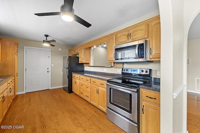 2329 S Willard Ave, Joplin, MO 64804 - kitchen with appliances with stainless steel finishes, arched walkways, light wood finished floors, dark countertops, and a ceiling fan