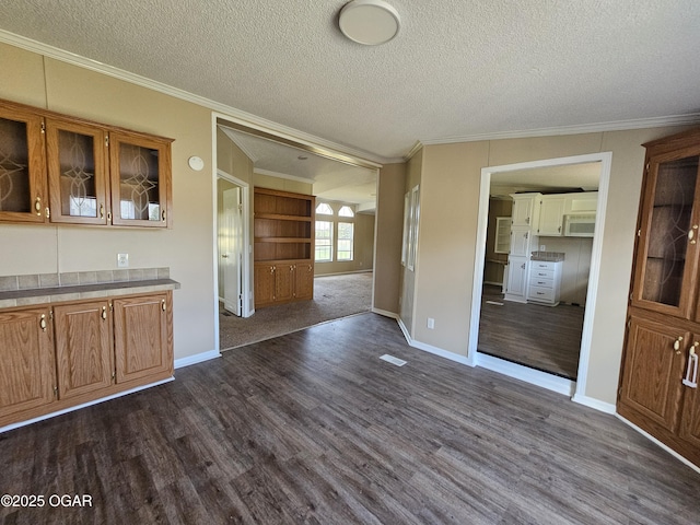 205 College St, Stark City, MO 64866 - kitchen featuring white microwave, crown molding, dark wood-style floors, glass insert cabinets, and brown cabinets