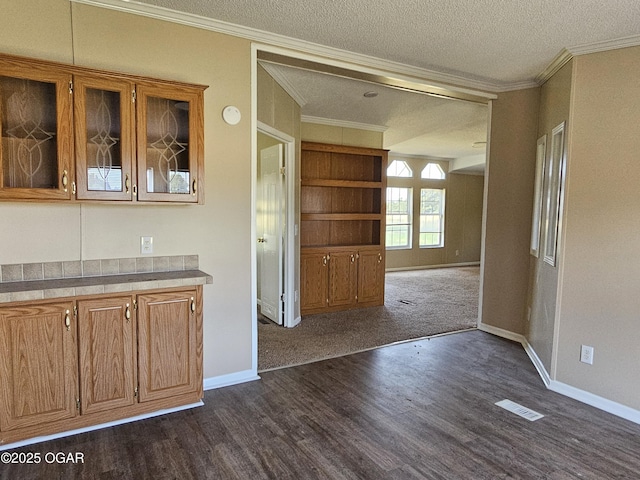 205 College St, Stark City, MO 64866 - kitchen with dark wood-style flooring, glass insert cabinets, crown molding, brown cabinetry, and a textured ceiling