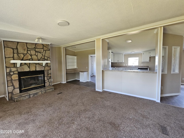 205 College St, Stark City, MO 64866 - unfurnished living room featuring ornamental molding, a textured ceiling, dark carpet, and a stone fireplace