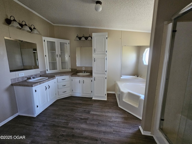 205 College St, Stark City, MO 64866 - bathroom featuring a textured ceiling, double vanity, a bath, ornamental molding, and wood finished floors