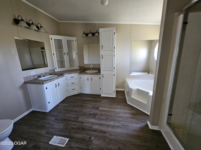205 College St, Stark City, MO 64866 - bathroom featuring double vanity, wood finished floors, a textured ceiling, a bath, and ornamental molding