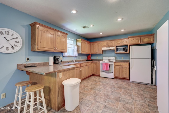 1717 Logan Drive `, Webb City, MO 64870 - kitchen featuring white appliances, under cabinet range hood, a peninsula, a kitchen breakfast bar, and recessed lighting