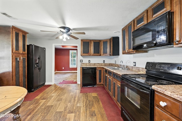 624 N Devon St, Webb City, MO 64870 - kitchen with black appliances, brown cabinets, dark wood-style flooring, ceiling fan, and glass insert cabinets
