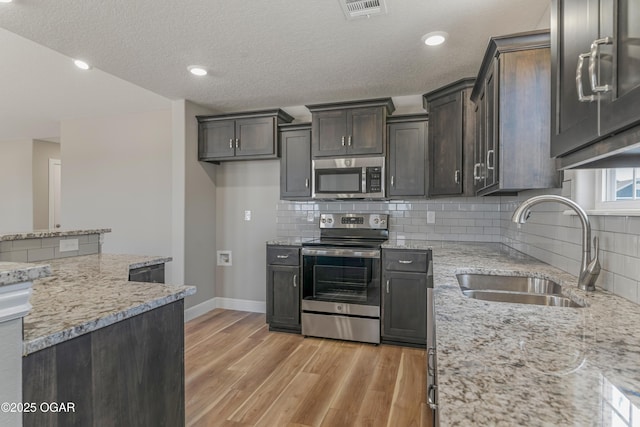 1220 Sheila Ann Dr, Carthage, MO 64836 - kitchen with stainless steel appliances, light wood-type flooring, light stone countertops, decorative backsplash, and recessed lighting