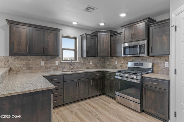 1224 Sheila Ann Dr, Carthage, MO 64836 - kitchen featuring stainless steel appliances, dark brown cabinetry, backsplash, light wood-style flooring, and light stone counters