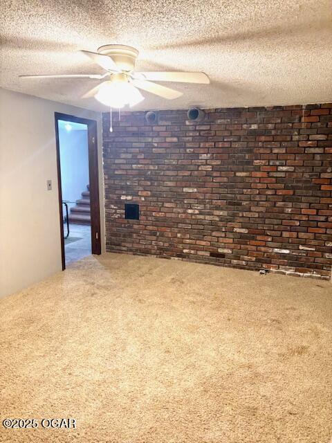 1606 Fairview Ave, Baxter Springs, KS 66713 - spare room featuring brick wall, carpet, stairs, ceiling fan, and a textured ceiling