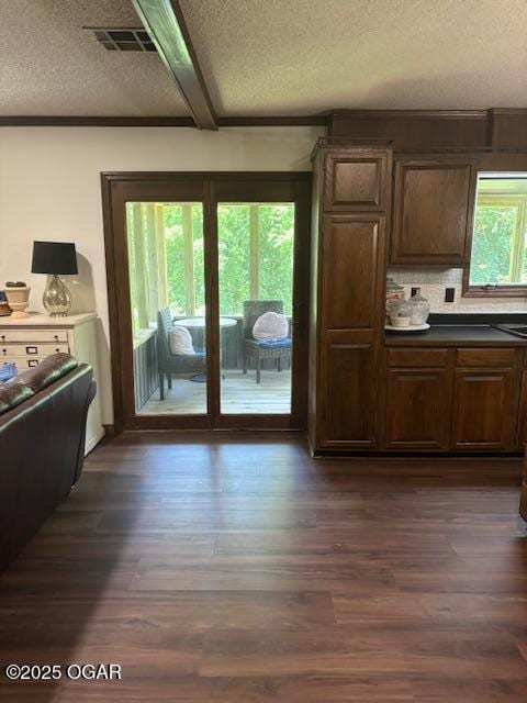 1606 Fairview Ave, Baxter Springs, KS 66713 - kitchen with a textured ceiling, dark wood-style flooring, decorative backsplash, and dark countertops