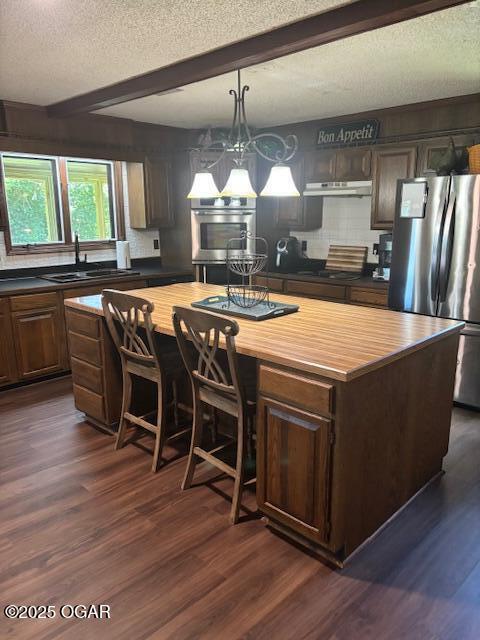 1606 Fairview Ave, Baxter Springs, KS 66713 - kitchen featuring freestanding refrigerator, butcher block countertops, a textured ceiling, a center island, and dark wood-style floors