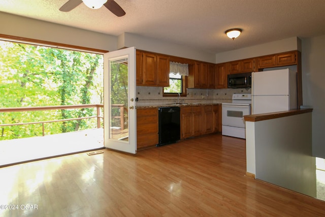 3619 Oak Ridge Dr, Joplin, MO 64804 - kitchen with black appliances, brown cabinetry, light countertops, light wood-style floors, and a textured ceiling