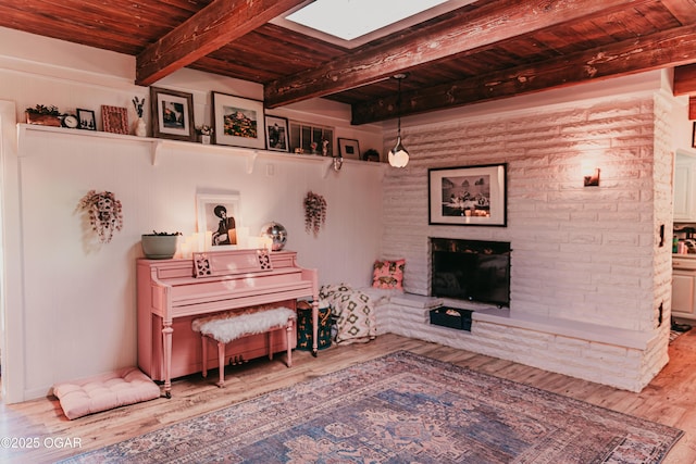 706 S Broadview Dr, Springfield, MO 65809 - sitting room with wood finished floors, a fireplace with raised hearth, a wood ceiling with exposed beams, and a skylight