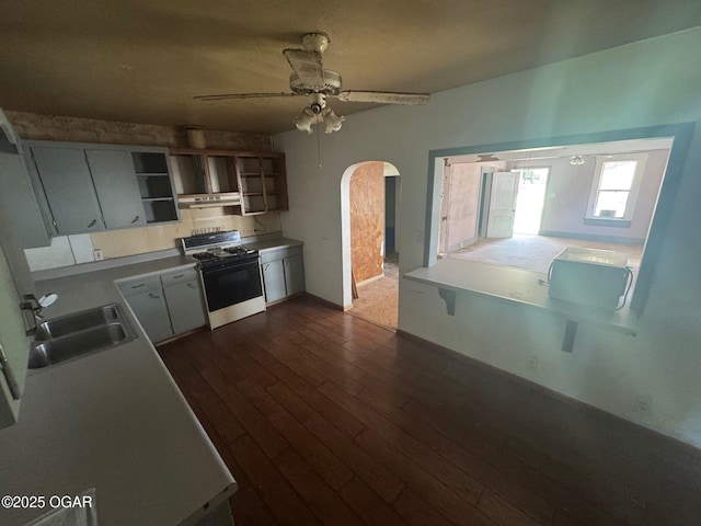 416 E 4th St, Baxter Springs, KS 66713 - kitchen featuring white range with gas stovetop, under cabinet range hood, open shelves, ceiling fan, and dark wood finished floors
