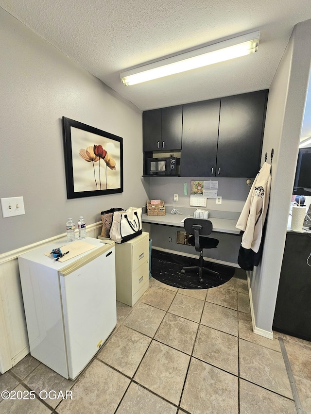310 W 19th St, Baxter Springs, KS 66713 - washroom featuring a desk, light tile patterned floors, and a textured ceiling