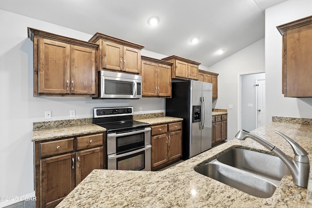 305 Anita Dr, Carl Junction, MO 64834 - kitchen with stainless steel appliances, lofted ceiling, light stone counters, recessed lighting, and brown cabinets
