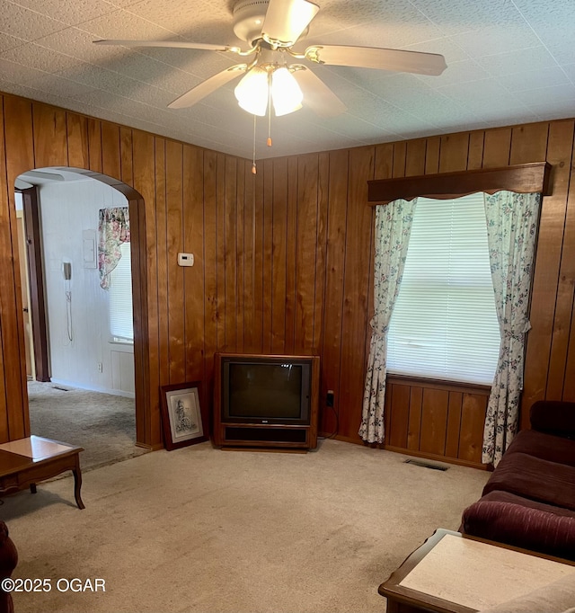 721 W Chestnut, Carthage, MO 64836 - carpeted living area with wood walls, plenty of natural light, a ceiling fan, and arched walkways