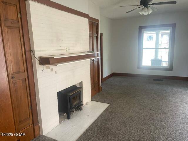 530 N Pearl Ave, Joplin, MO 64801 - unfurnished living room featuring a ceiling fan, a wood stove, and carpet floors